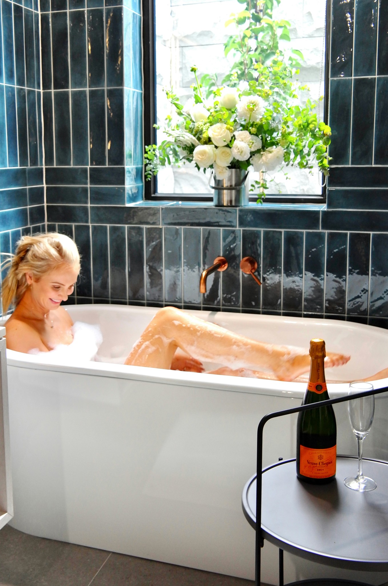 a person in a bathtub with a bottle of wine and a glass of wine