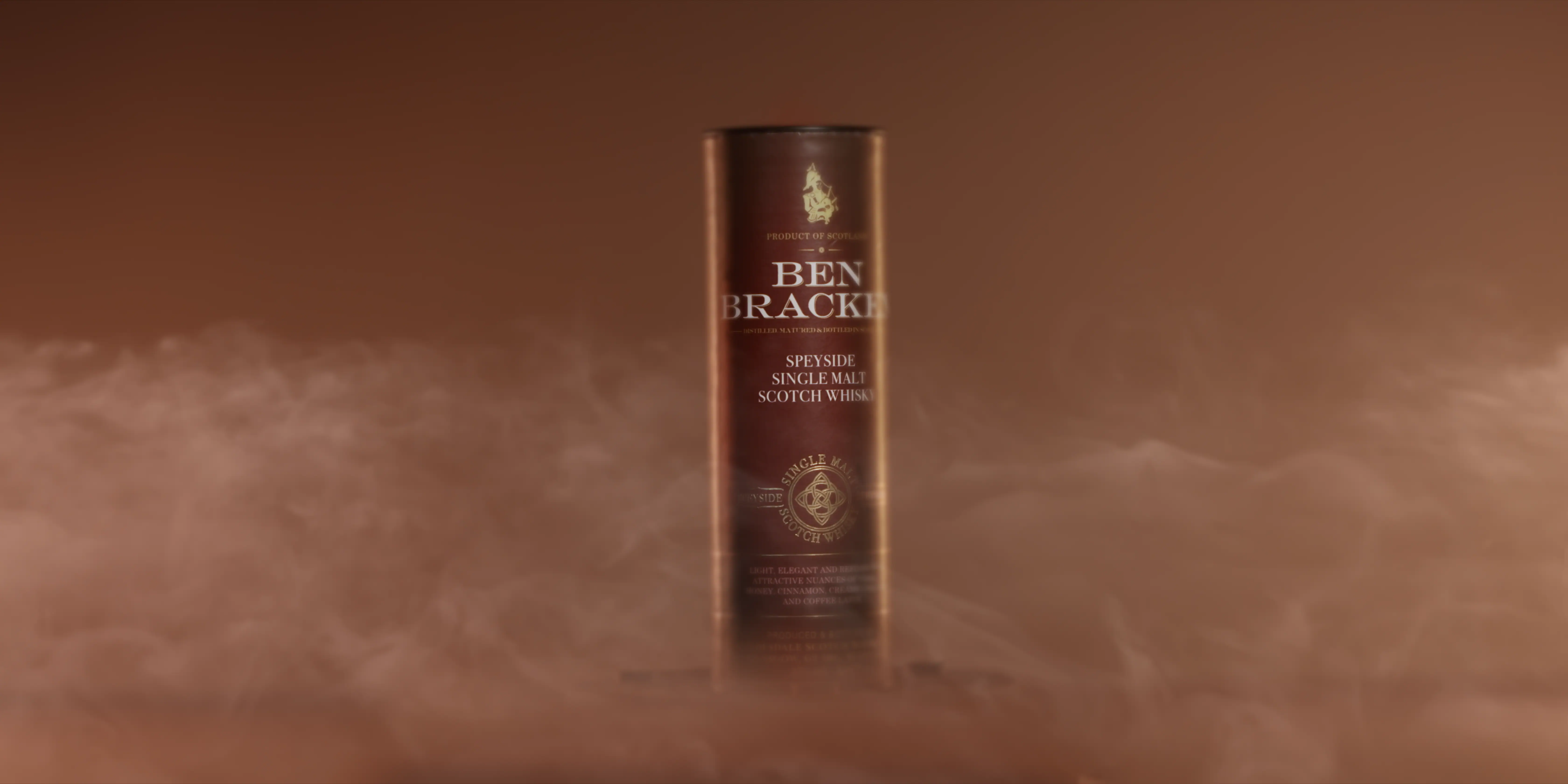 A cylindrical bottle of Ben Bracken Scotch Whisky is enveloped in wisps of mist against a warm, brownish background, emphasizing its luxurious packaging.