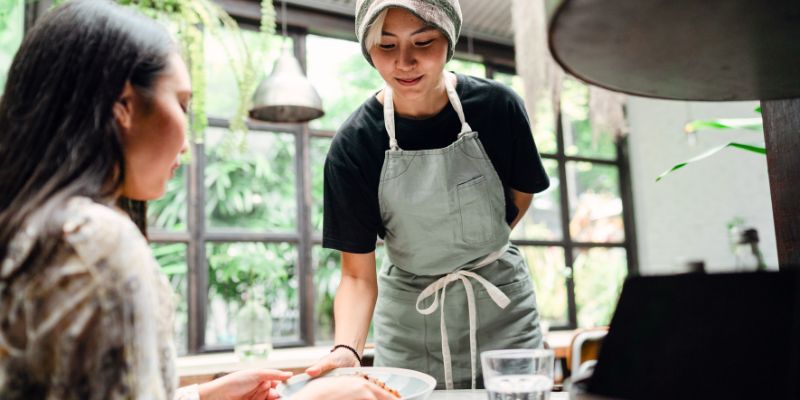 一名马来西亚服务员在咖啡馆为顾客上菜