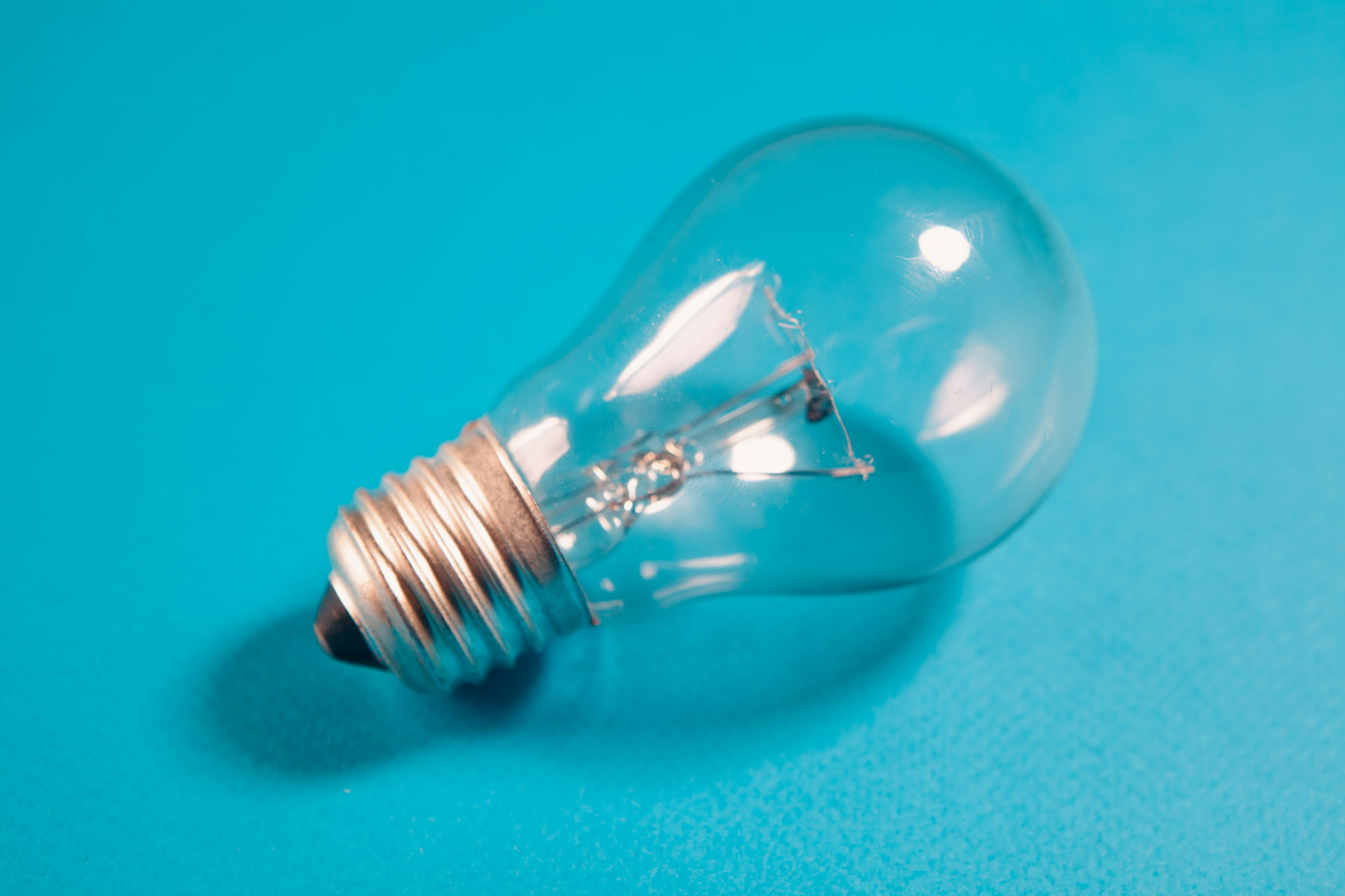 A clear incandescent light bulb on a blue background.
