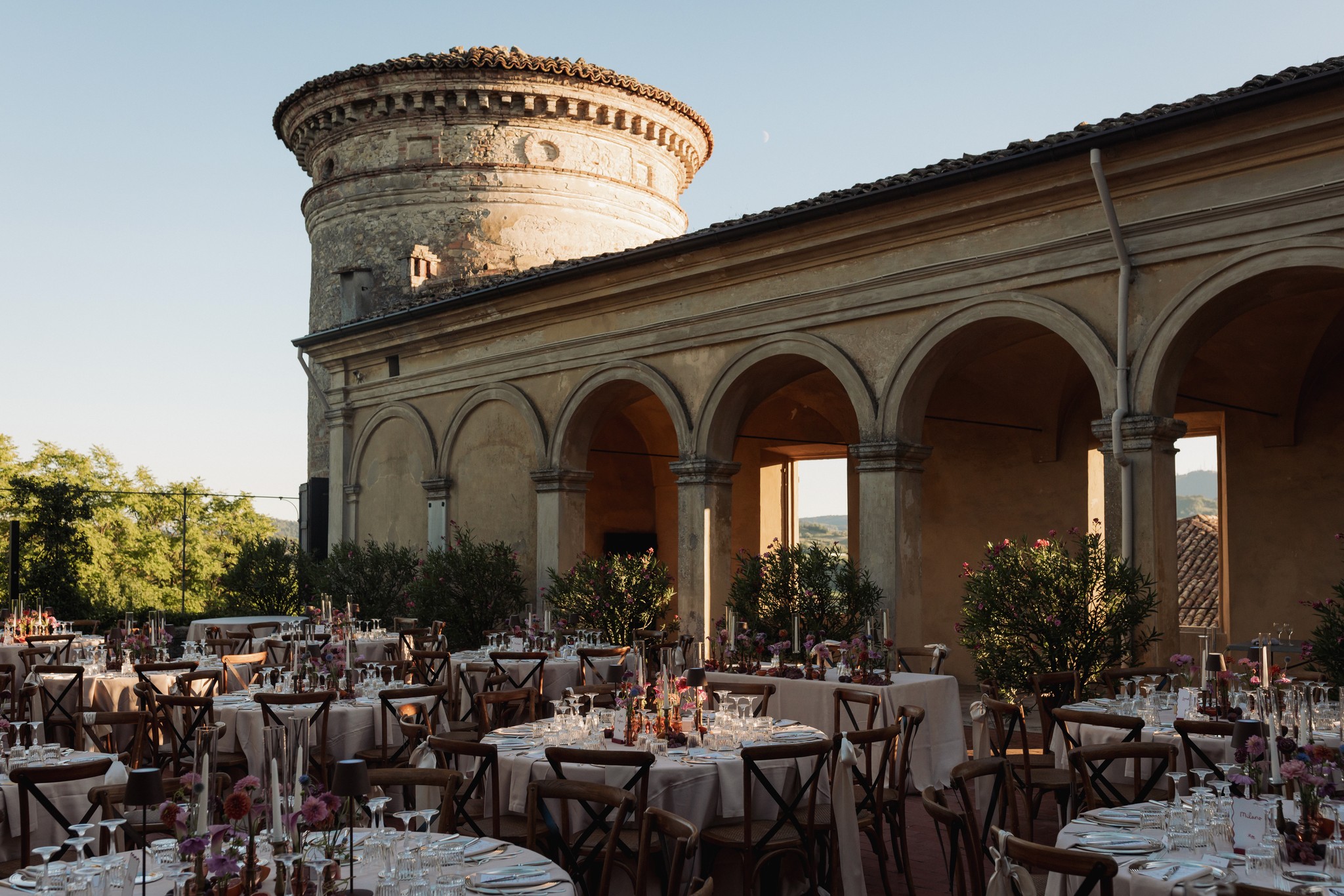 Ricevimento di matrimonio nel loggiato del Castello di Scipione, tavoli apparecchiati sotto le arcate storiche al tramonto