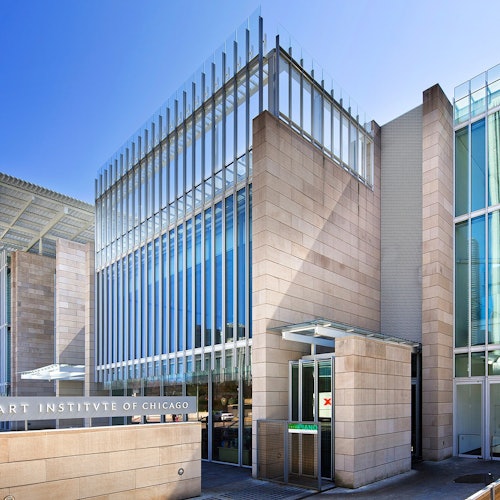 Modern glass and stone building facade with signage indicating "Art Institute of Chicago" under a clear blue sky.