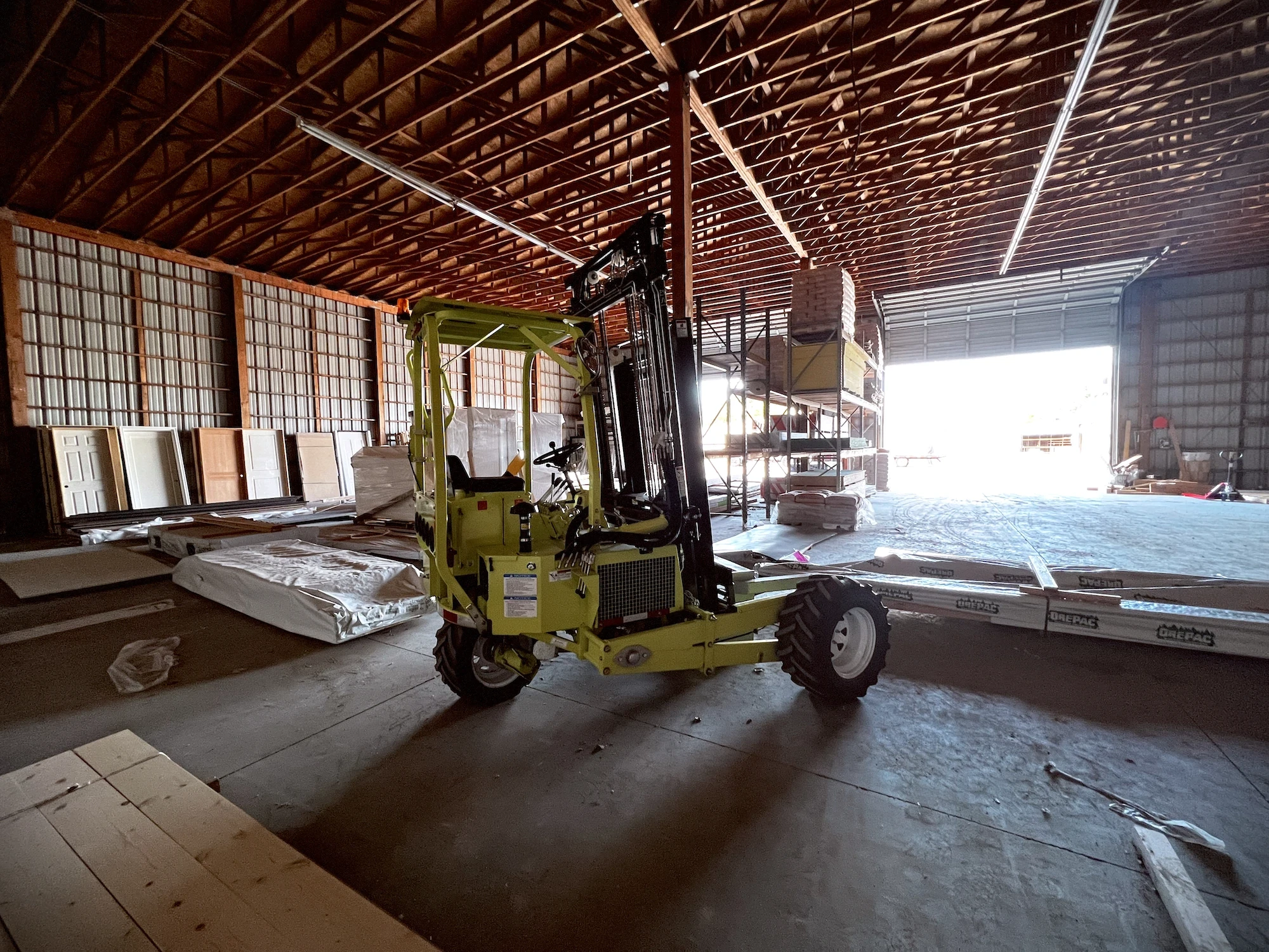 Capital Lumber forklift moving long material inside covered yard storage