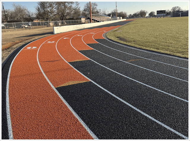 Newly resurfaced orange and black running track straightaway with smooth surface and white lane lines