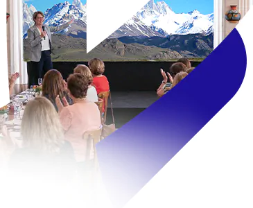 Apresentadora da Livare Viagens conduz a abertura oficial do Circuito Andino, com grupo de viajantes reunidos em auditório e imagem de Machu Picchu ao fundo no telão.