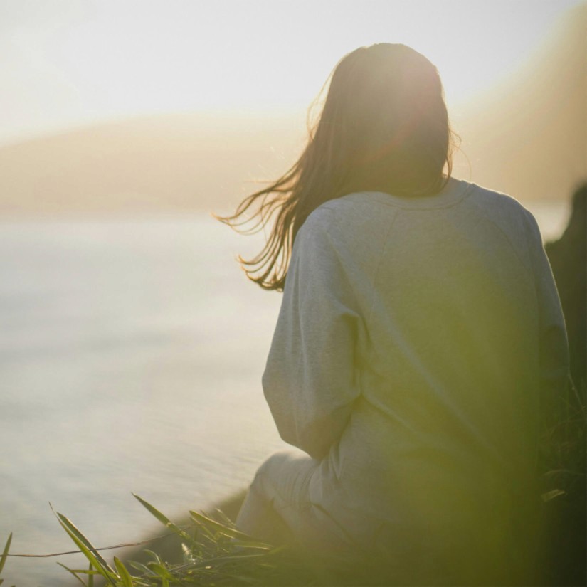 woman looking at water at sunrise