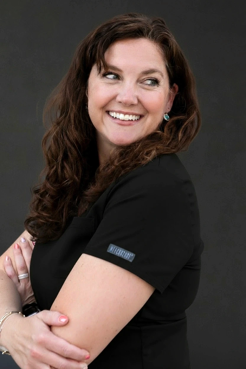 Portrait of Nurse Practitioner Melinda O’Neal smiling outdoors in blue medical scrubs, Meridian Medical Aesthetics.