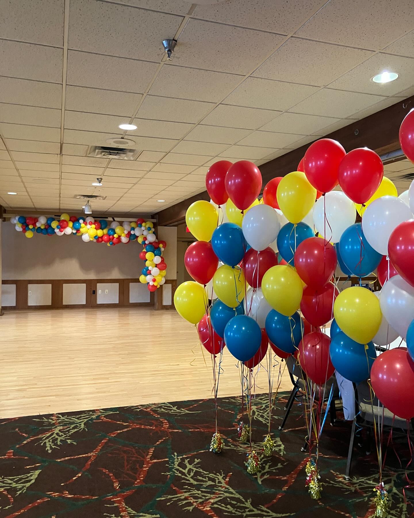 Colorful balloon ceiling installation with red, blue, yellow, and green balloons arranged for an indoor event by Be Bold Balloons