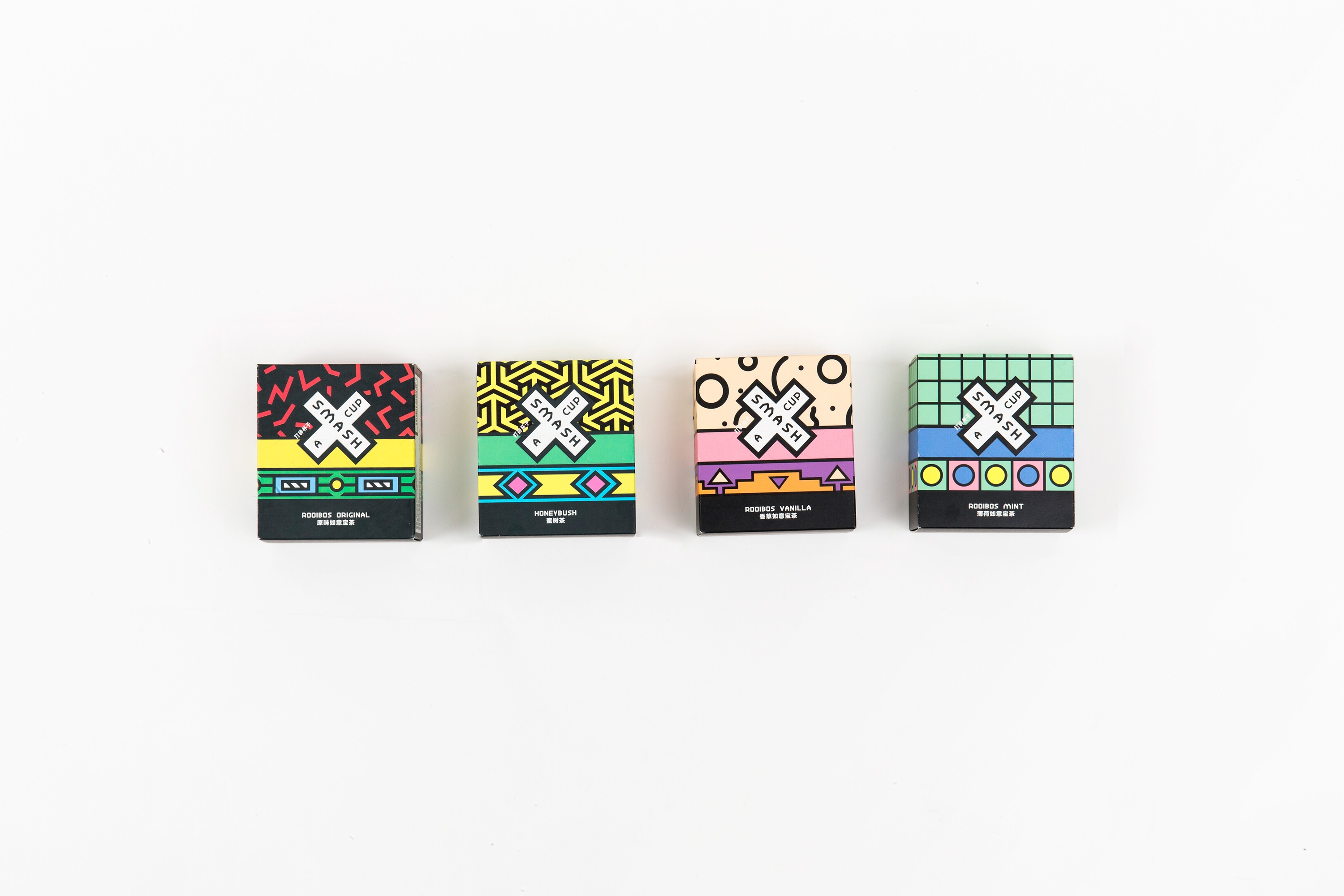 A photo showing four colored boxes with patterns and a white X in the middle. The text on the whit X is: Smash A Cup.