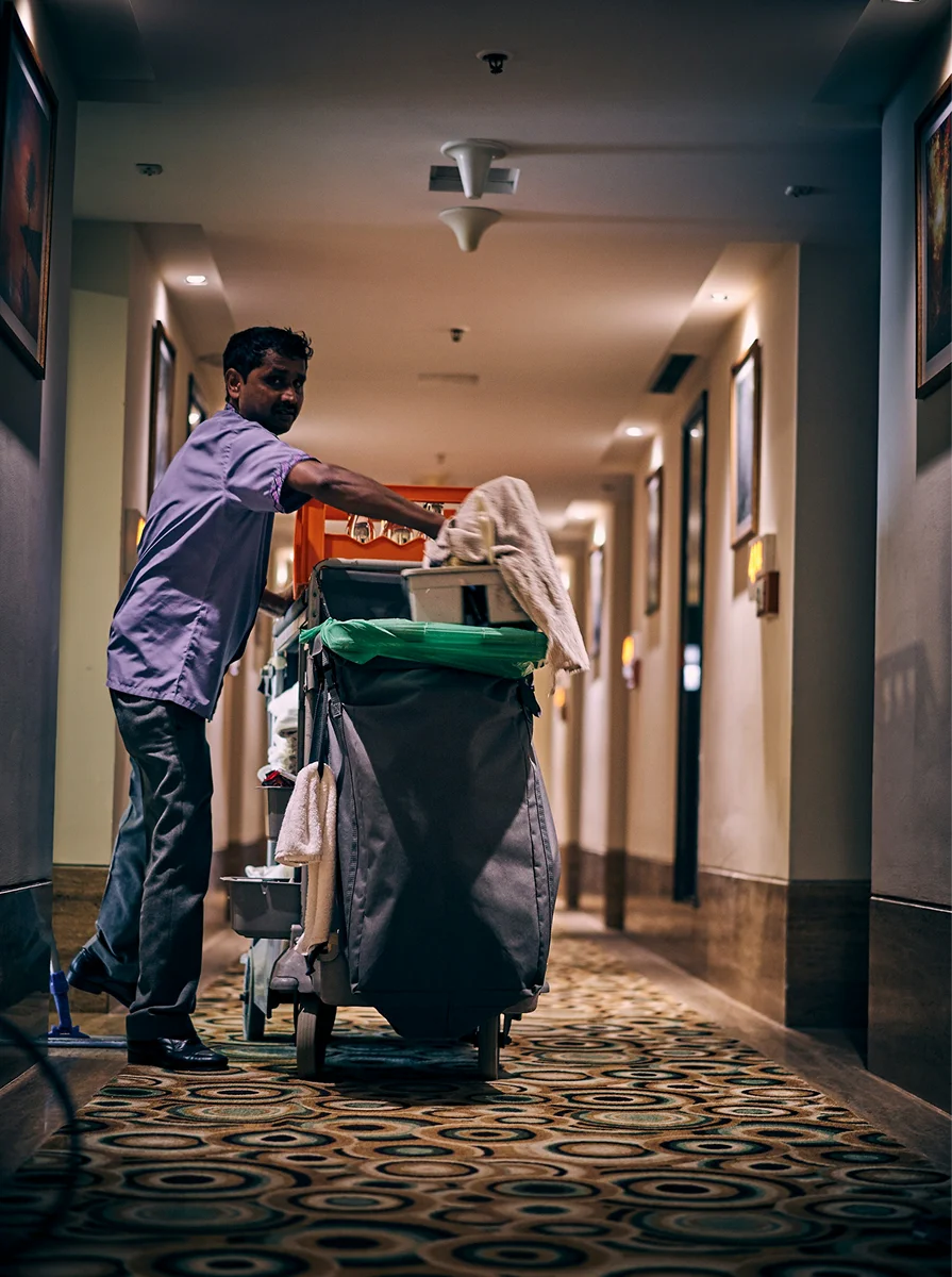 Housekeeper cleaning a hotel corridor.