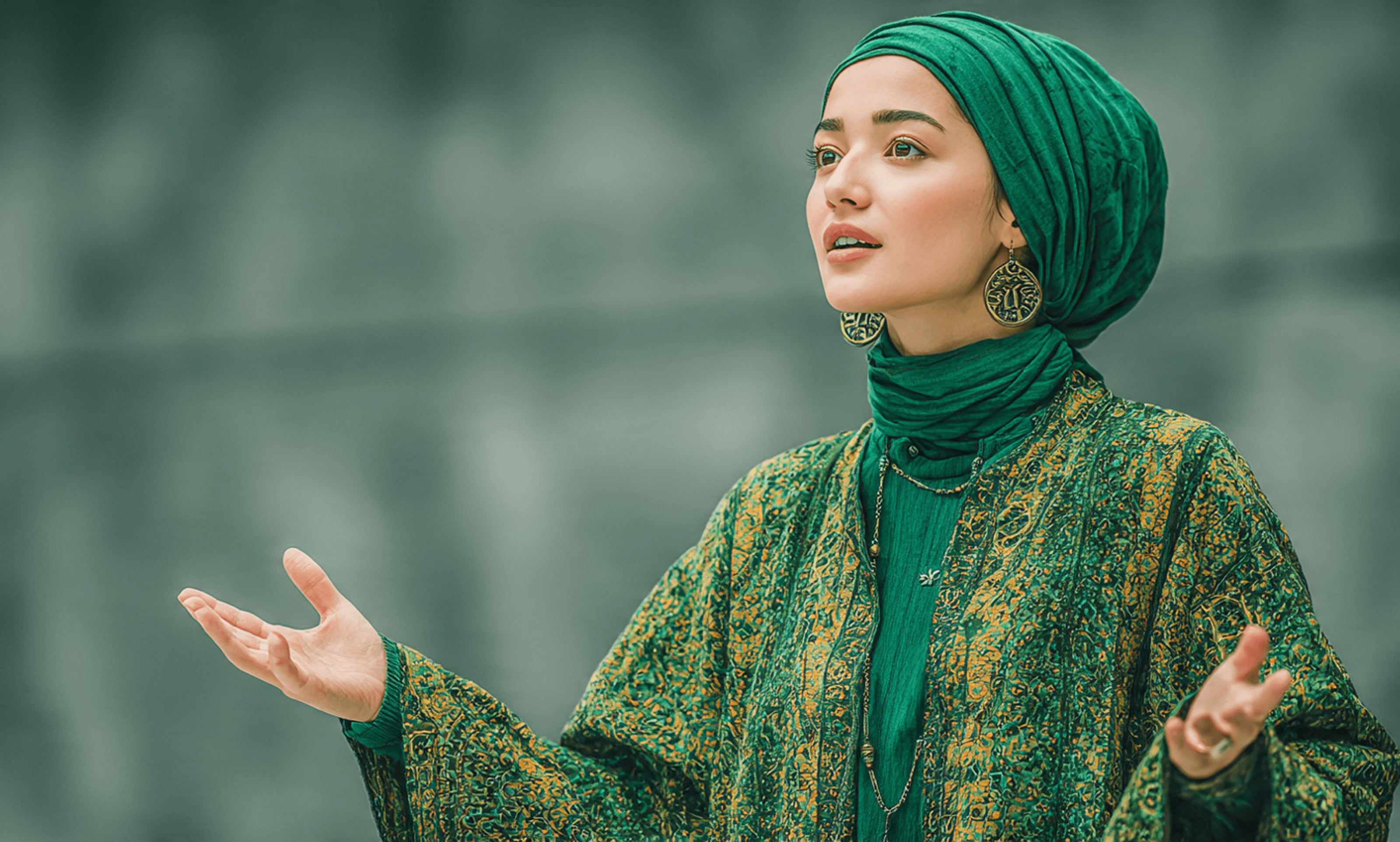 A woman in a green hijab and patterned robe gesturing with open hands while looking upwards.