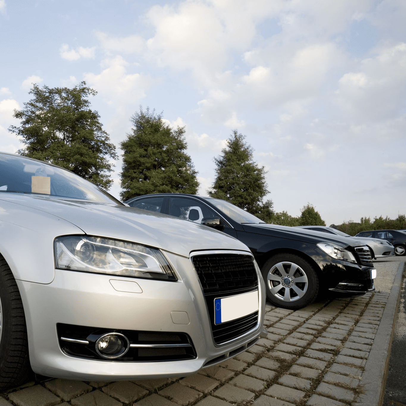 Cars parked in a row, silver and black vehicles.