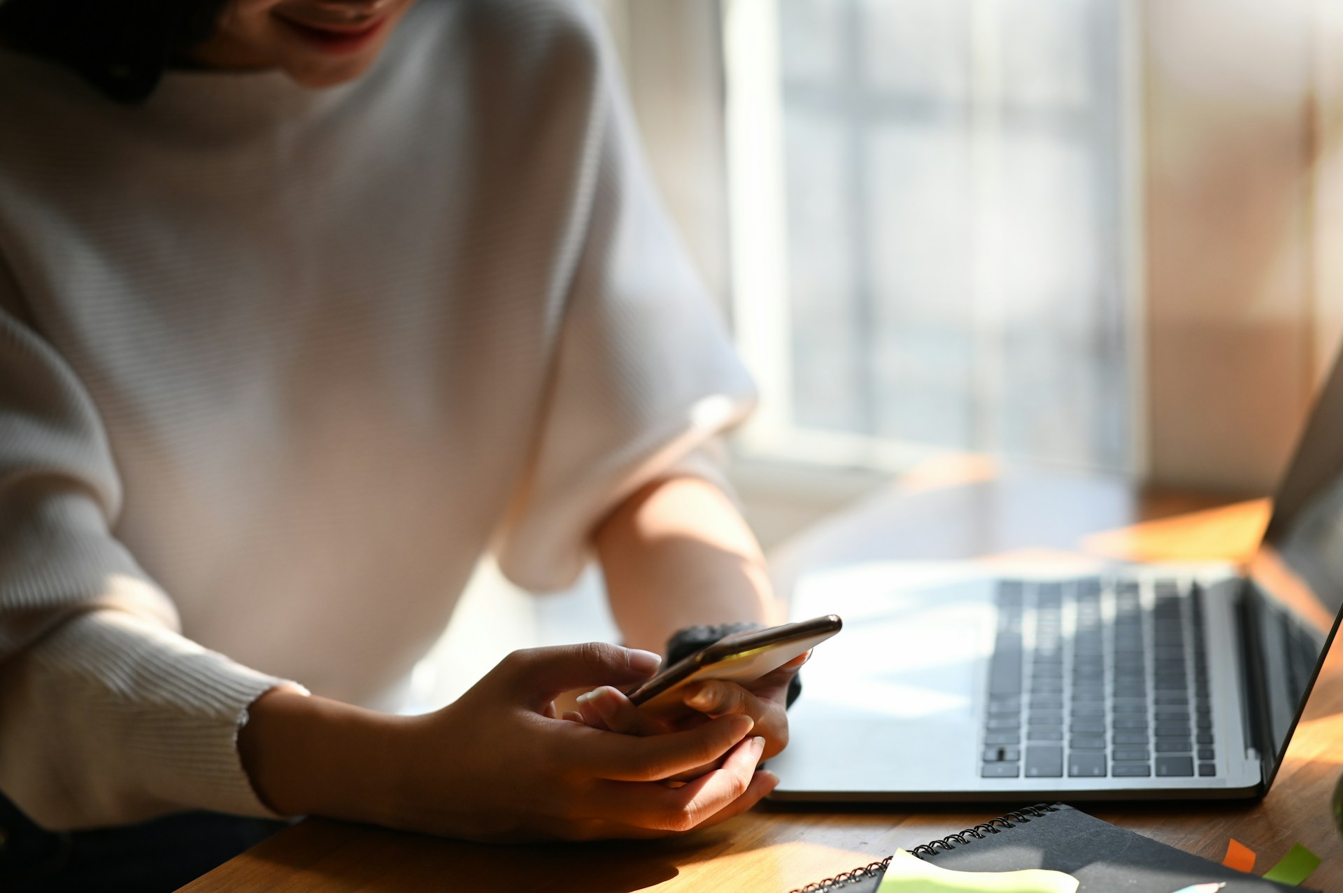 A person using a phone in front of a laptop