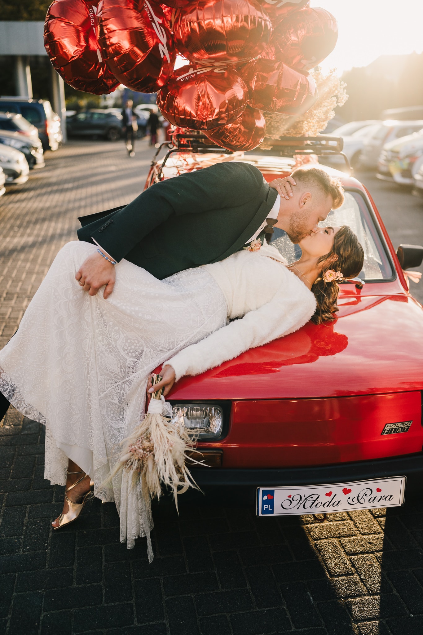 A couple stands hand-in-hand in front of a rustic stone building.