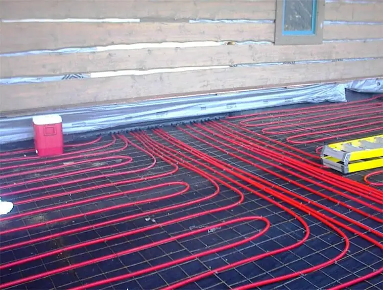 Red PEX radiant floor heat loops laid on wire mesh before the pour, log home