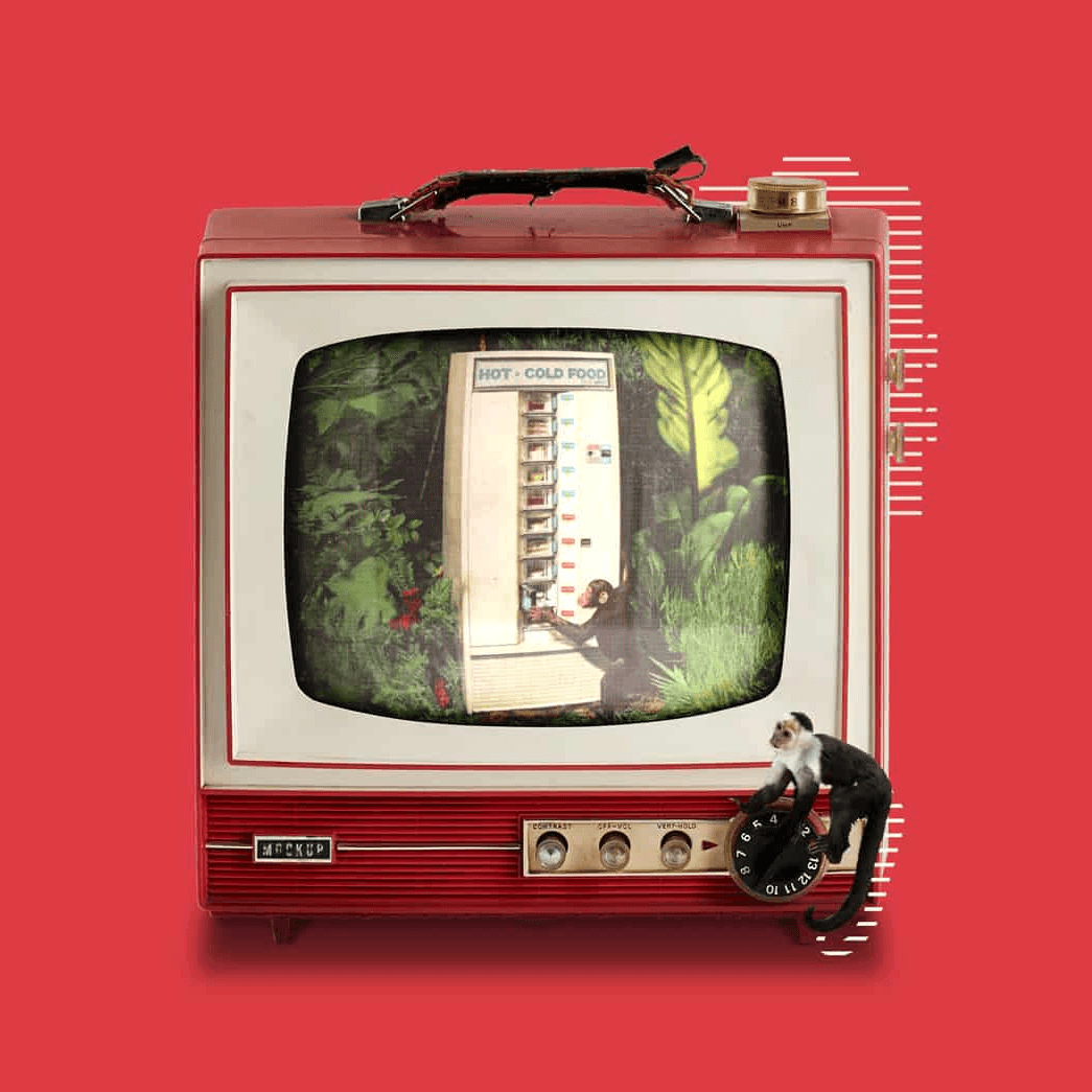Televisor retro rojo con venta de comida caliente y fría en pantalla, acompañado de un pequeño mono.
