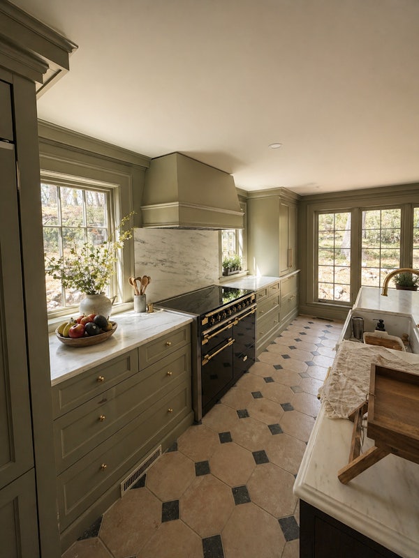 Sage inset cabinetry, honed marble slab, black enamel range