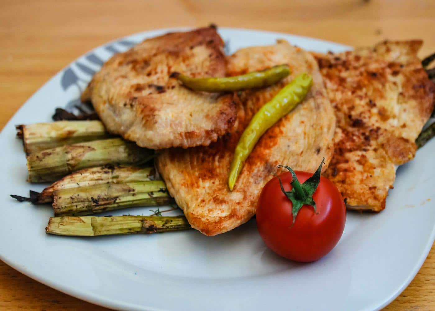 Chicken breasts on top of vegetables with a tomato on the side to showcase bland diet foods