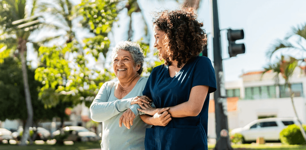 Senior woman and healthcare aide walking outside