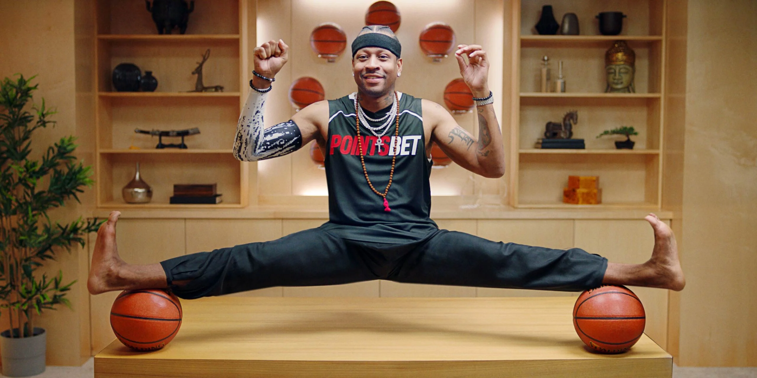 Basketball star in a PointsBet singlet doing a full split between two basketballs, from 'Allan Iverson is the answer'