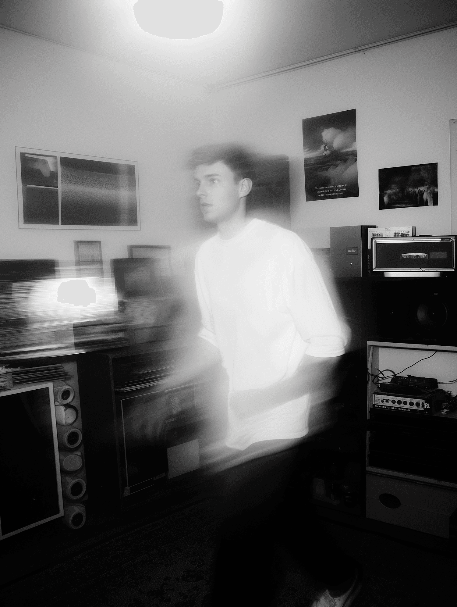 Man in a room with electronics and posters, captured with strong motion blur