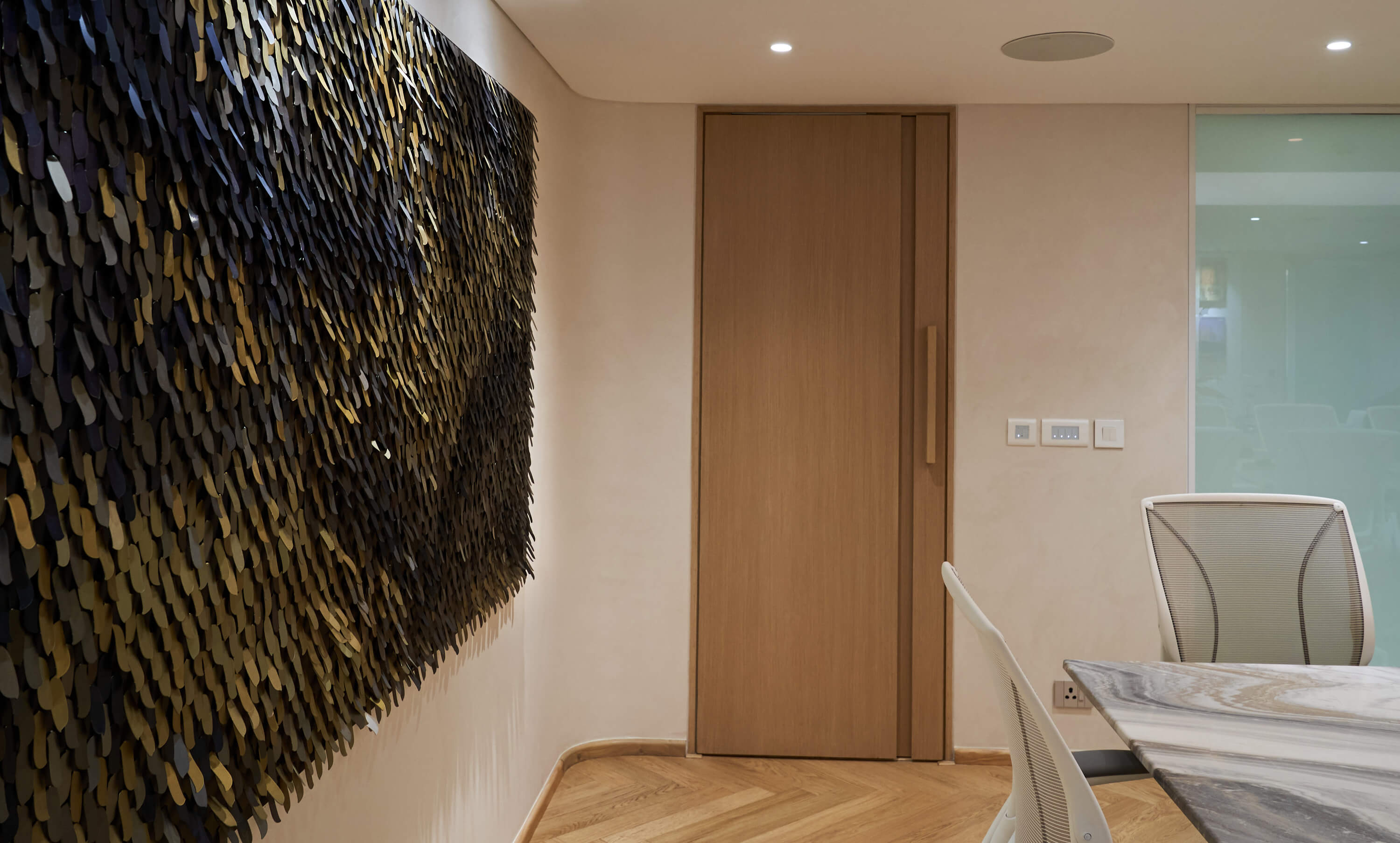 Textured black and gold abstract wall art in modern meeting room.