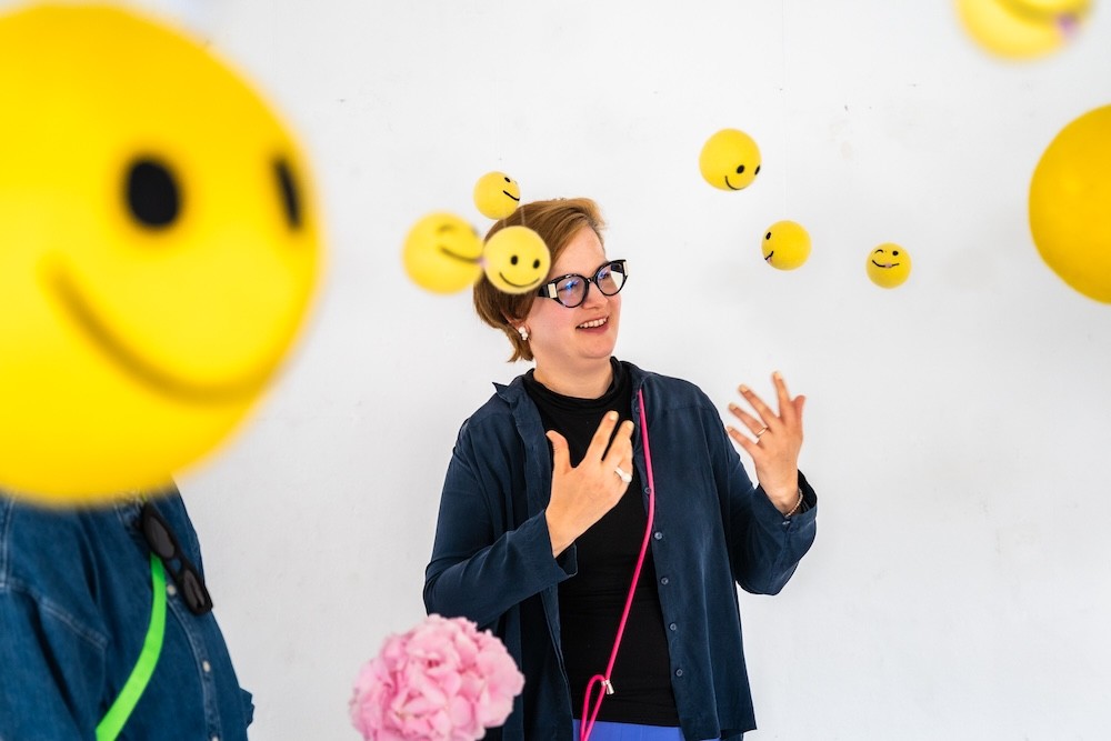Inštalácia so žltými smiley objektmi v priestore, interakcia návštevníkov