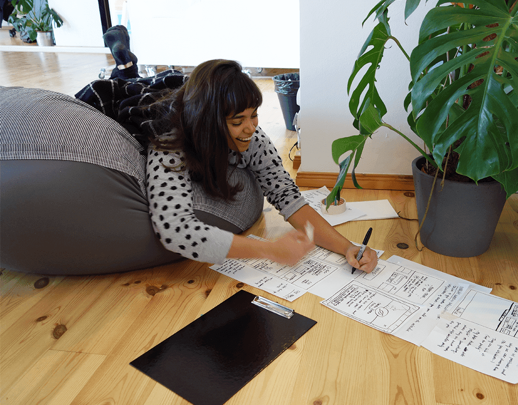 Woman leaning on a beanbag sketching and planning work on paper in a home workspace