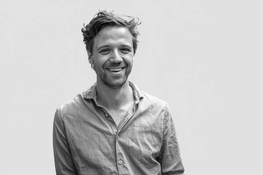 Black and white portrait of a smiling person with curly hair