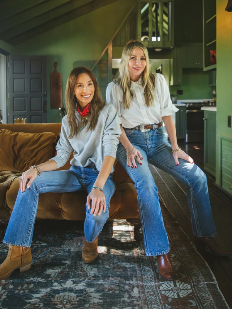 Two women in jeans sitting on a sofa
