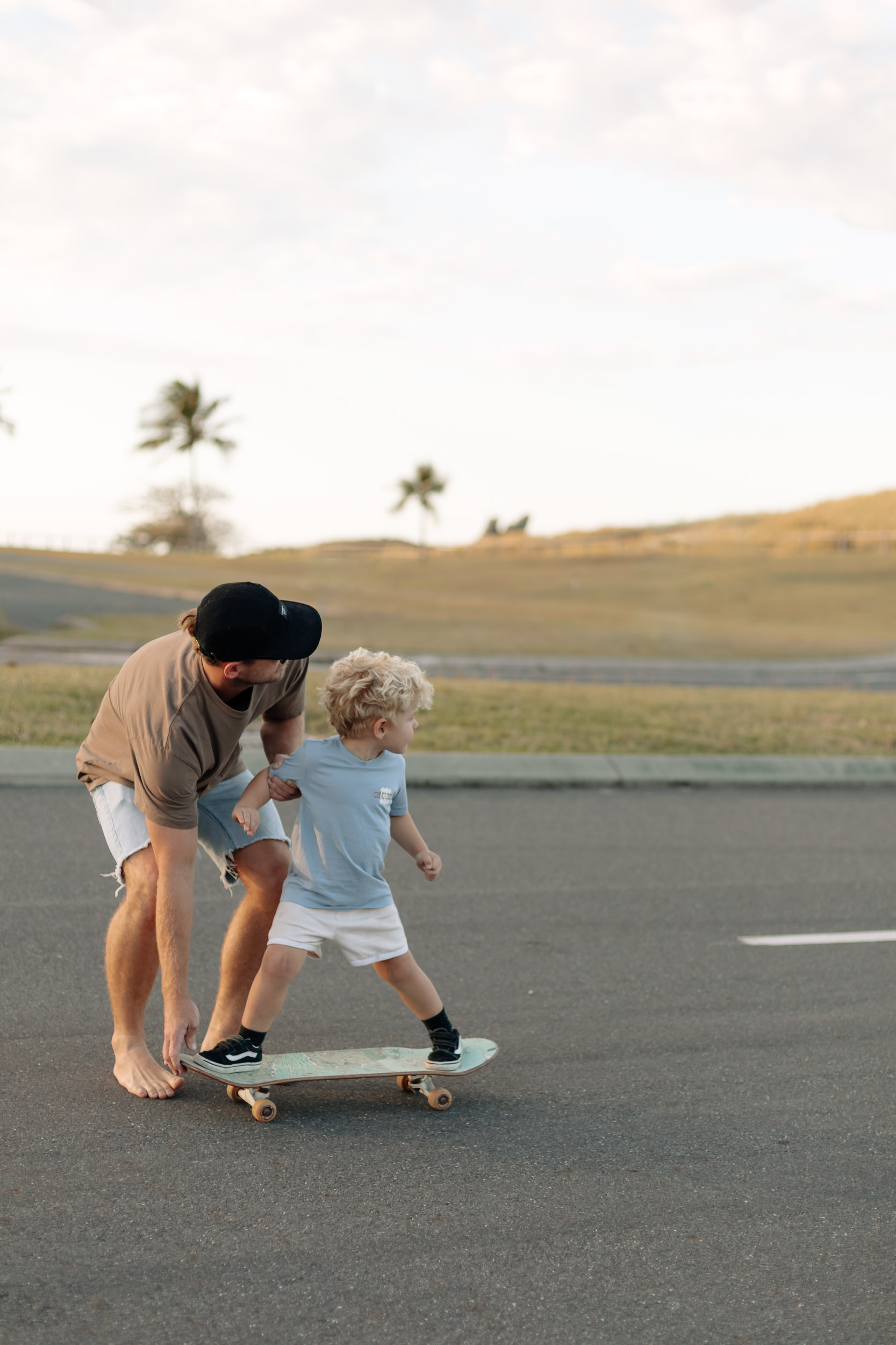 Father teaching his child to skateboard on an urban street during a relaxed family photo session in Mackay.