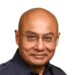 A man wearing glasses and a gray buttoned up shirt.