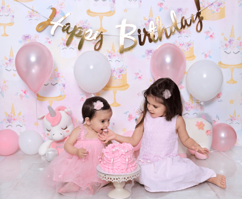 Baby celebrating her first birthday celebration with a sibling.