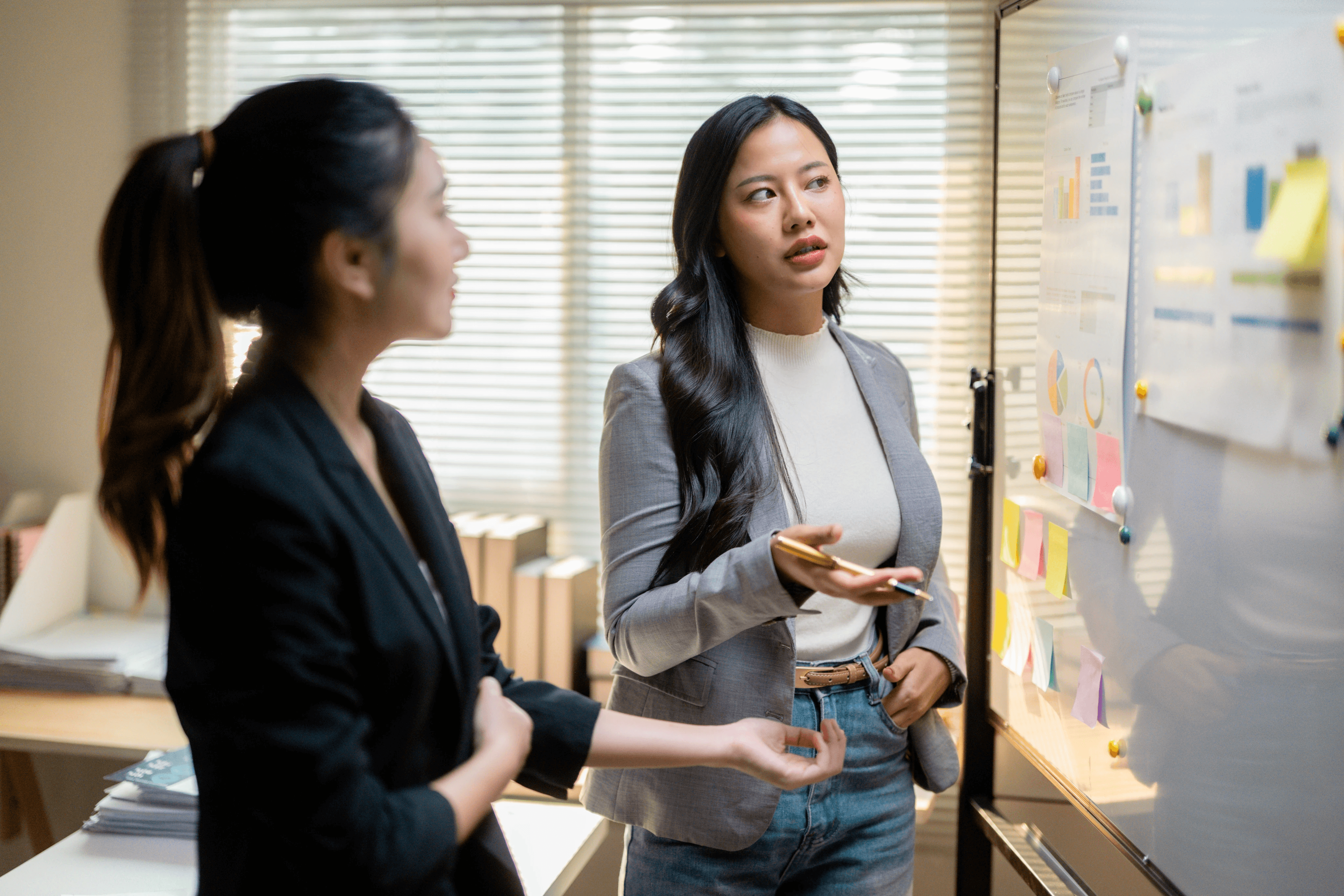 Two researchers discussing insights on a whiteboard with charts and sticky notes