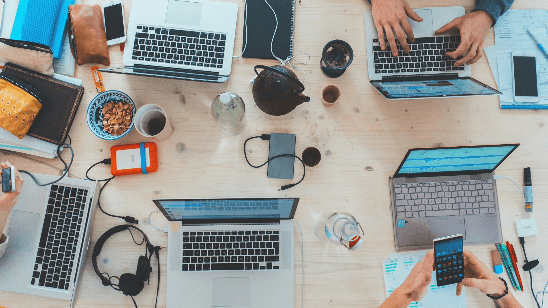 A shot looking down at a desk filled with laptops, mobile phones and other work-related items