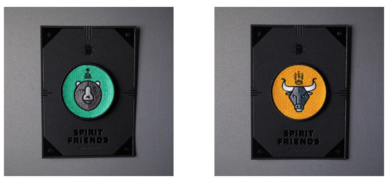 A photo of two colored patches one green with a bear design on it, the other yellow orange with an bull design on it.