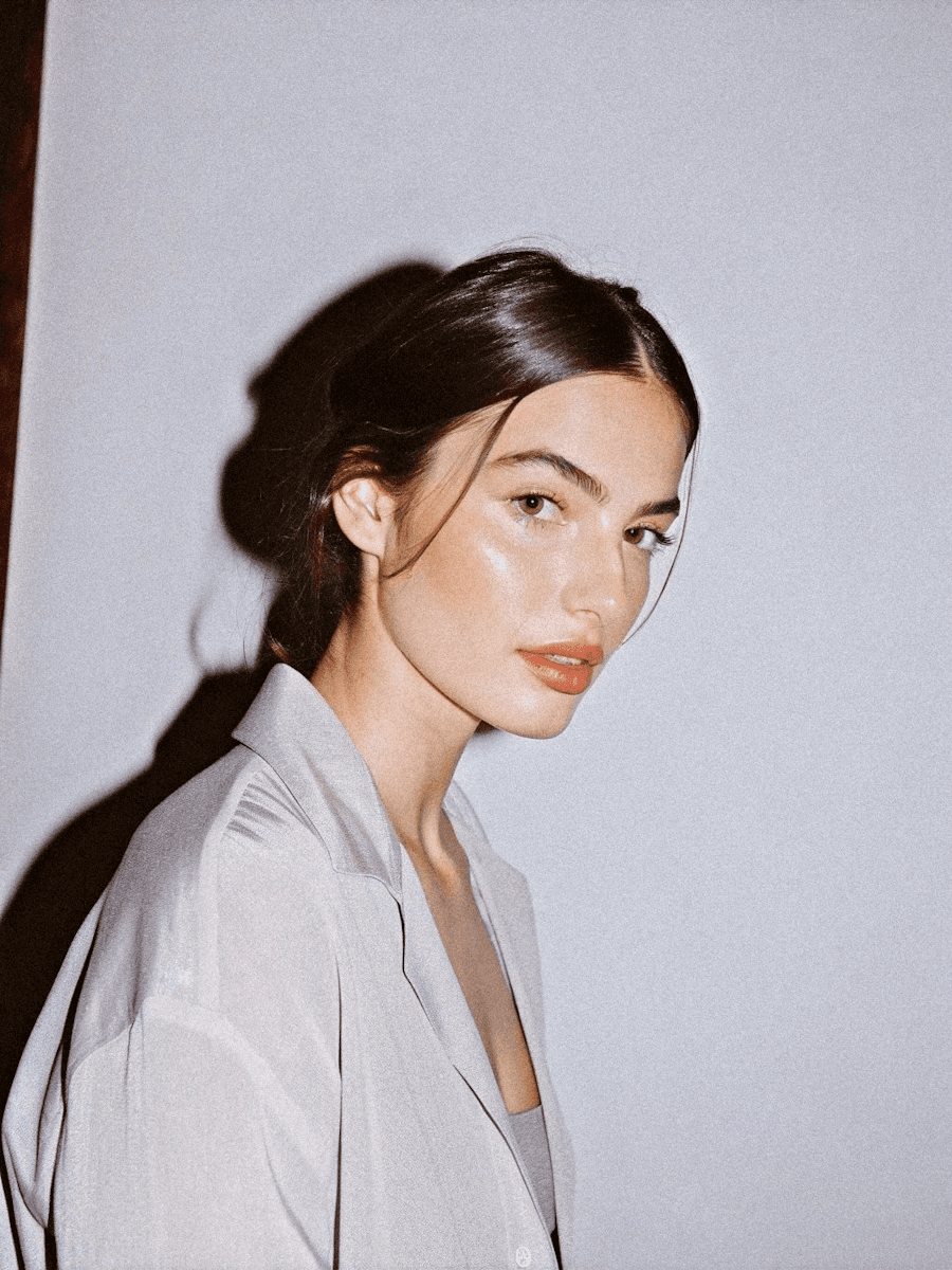 Woman in a white shirt, editorial portrait against a light grey background