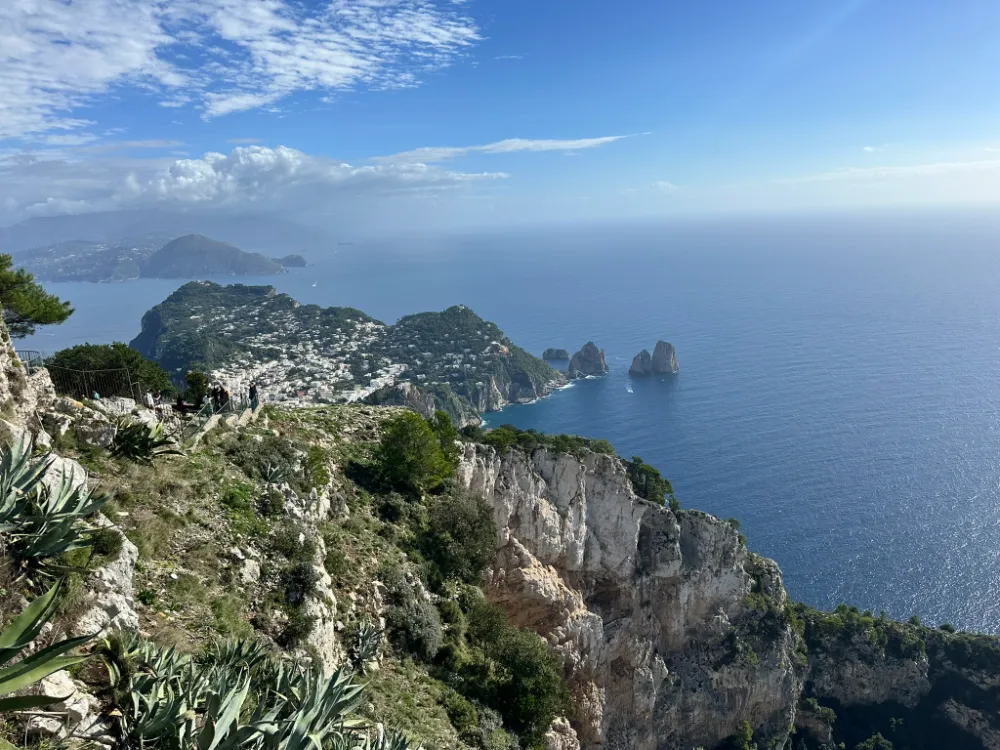 Capri's cliffs and the Faraglioni rocks seen from a clifftop viewpoint above the sea.