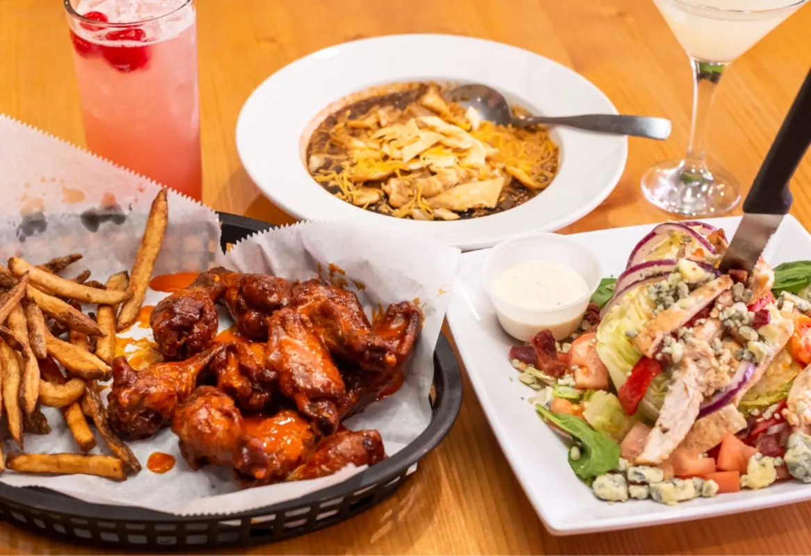 Wings, chili and salad on a wood table