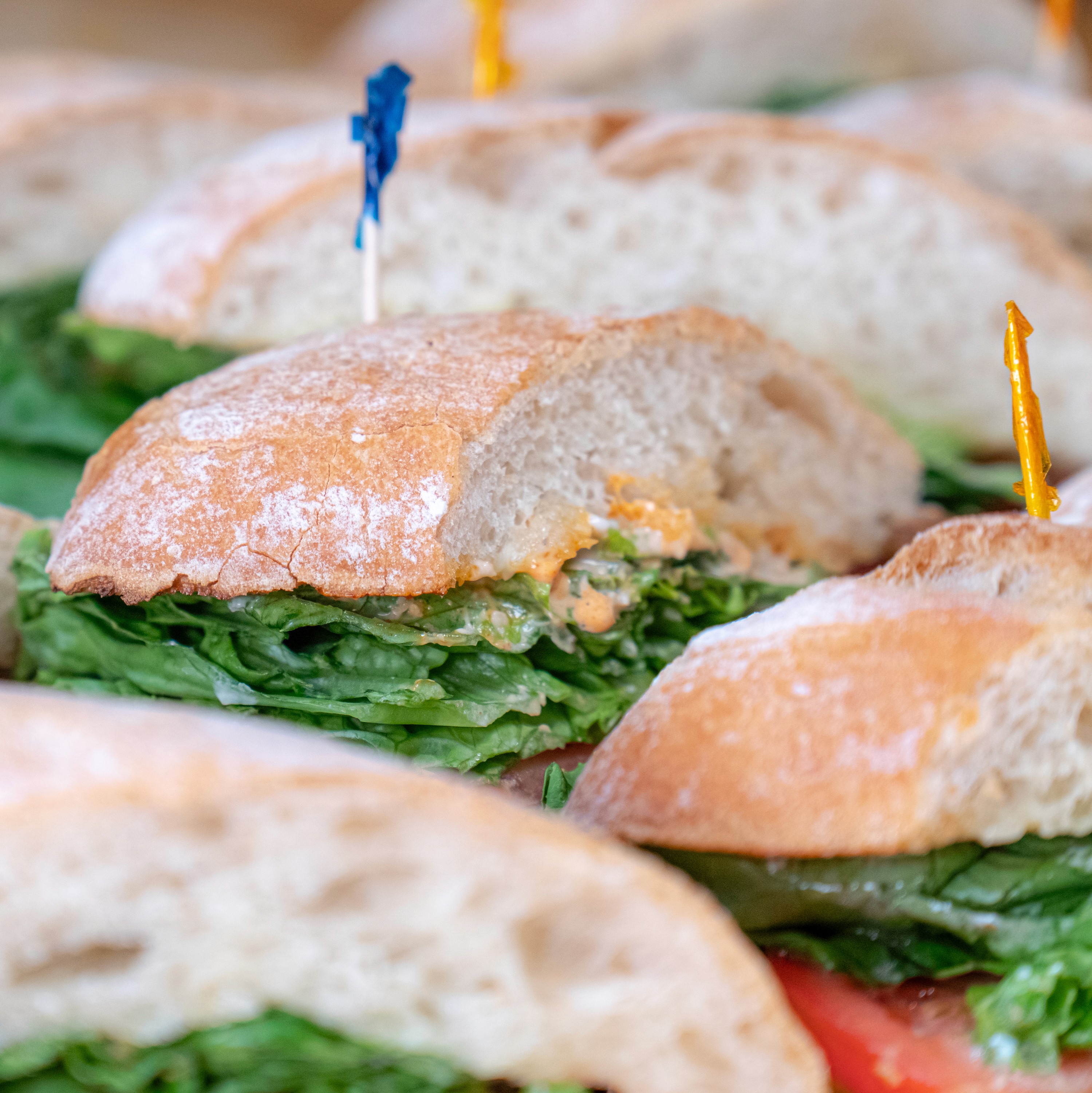Made-to-order Italian sandwich halves with lettuce and tomato on ciabatta