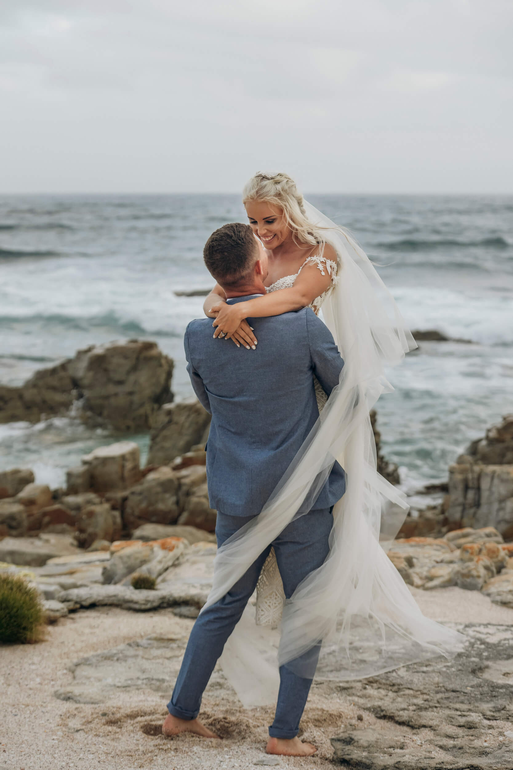 Groom lifting bride on beach with ocean backdrop at Mostertshoek wedding