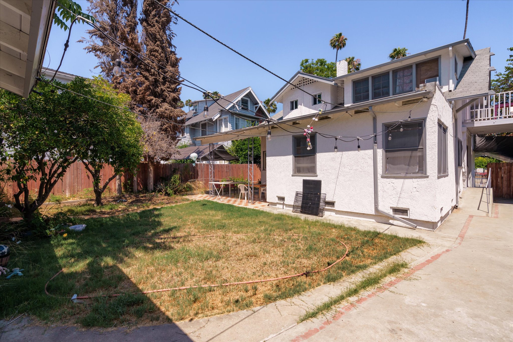 A sunny backyard at 1807 n van ness, with grass, a tree, and a white shed against a clear blue sky.