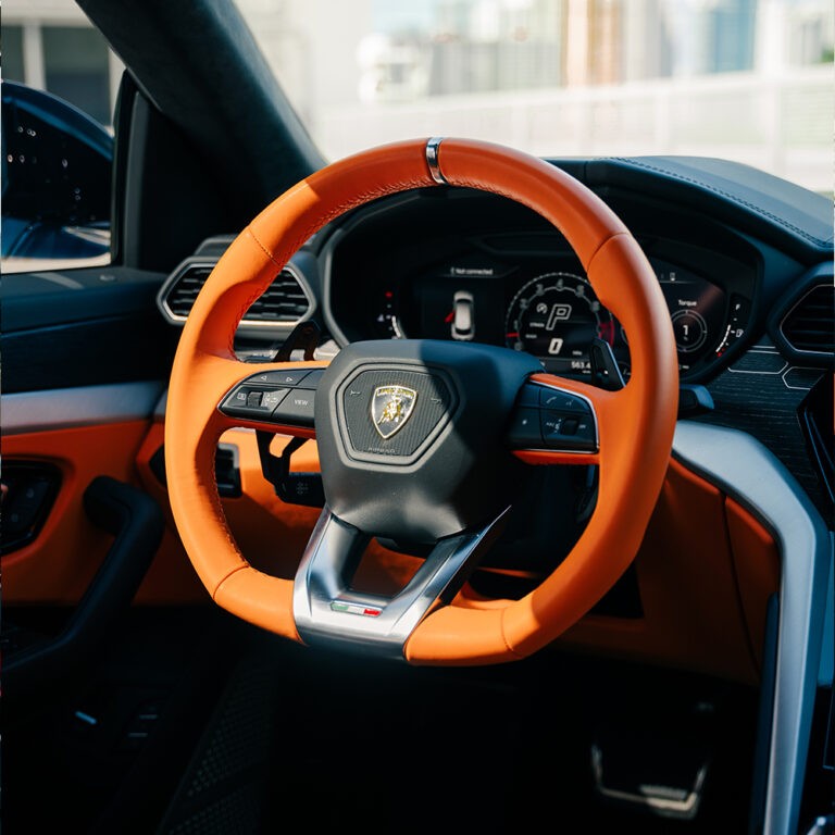 Lamborghini Urus S interior, orange and black accents, luxury SUV cockpit.