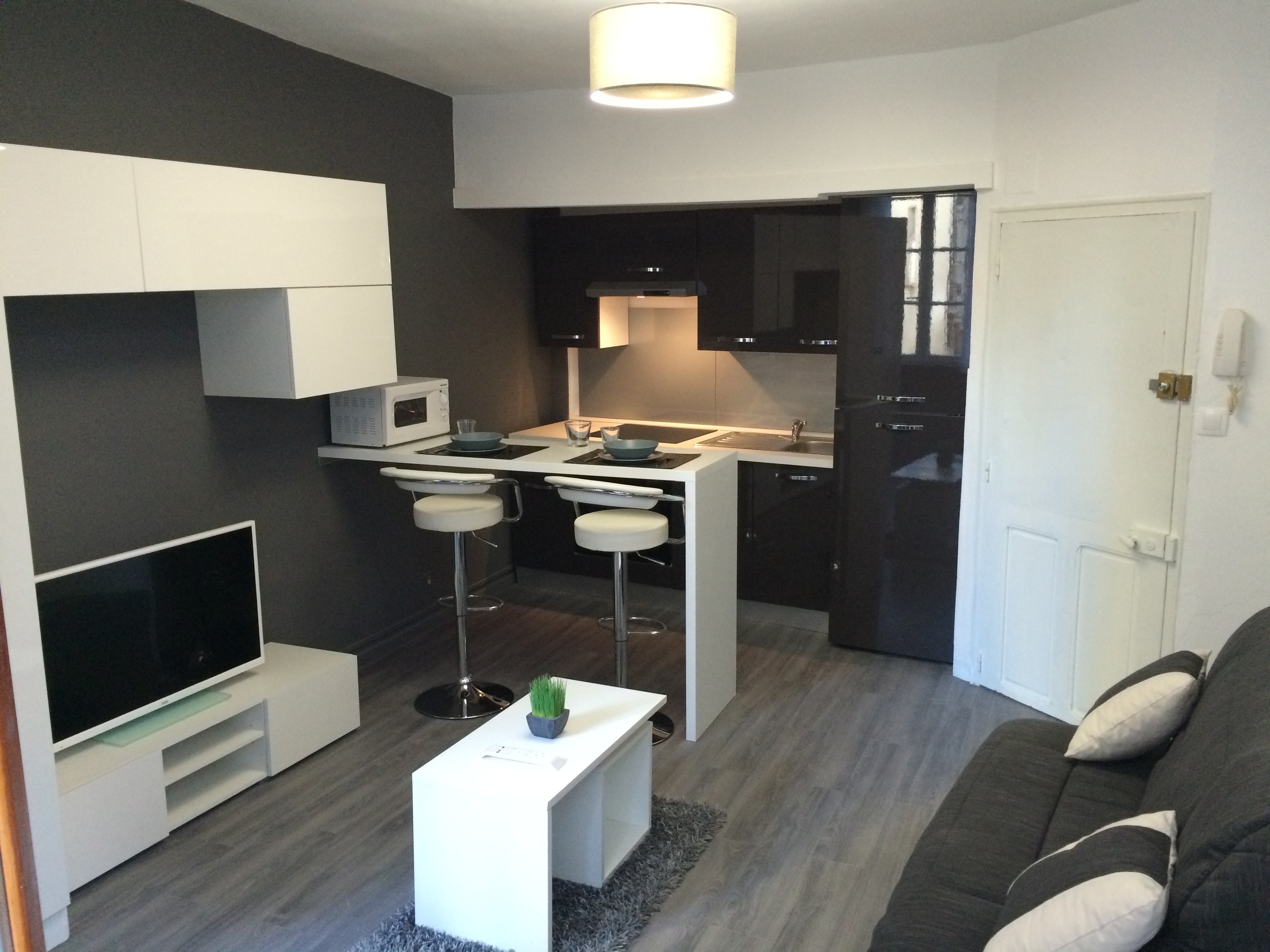 Modern two-story home with large glass windows, warmly lit interiors, and a balcony. Surrounded by trees and a manicured lawn at dusk. Cozy ambiance.