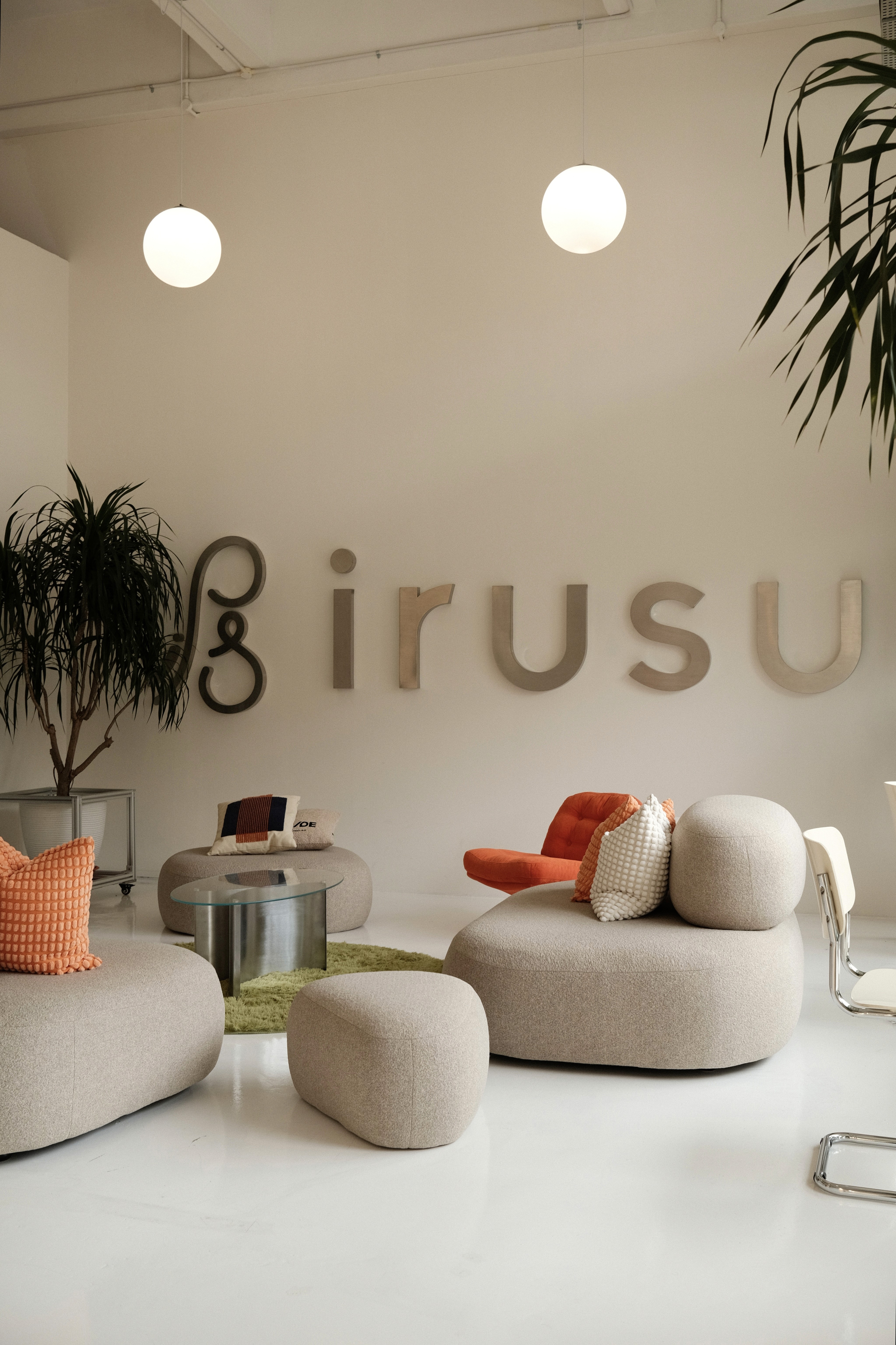 A soft, sculptural lounge setting defined by rounded forms, neutral upholstery, and subtle pops of colour, creating a relaxed yet design-forward communal space.