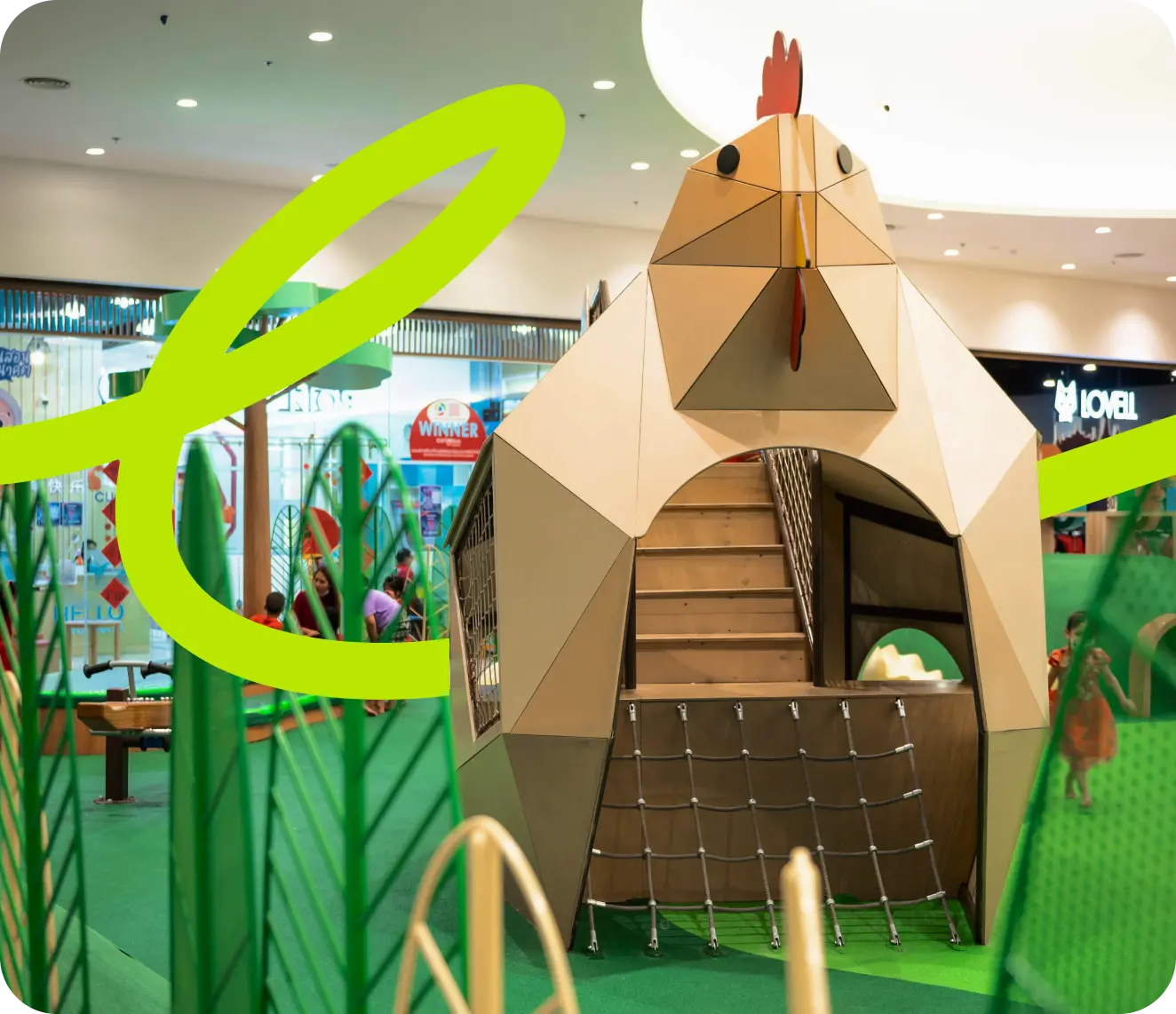 Colorful playground with green structures, a large clock, flowers, and city skyline in the background.