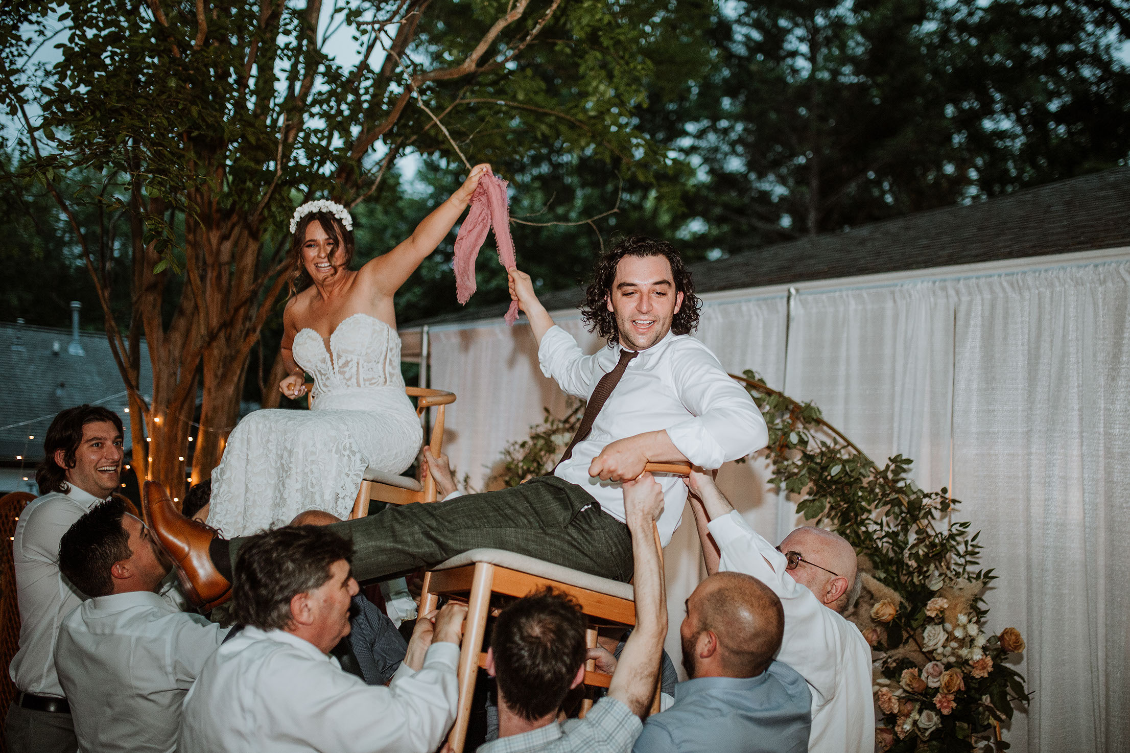 Flower Child Weddings reception design with floral tables, coral napkins, and woven chairs.