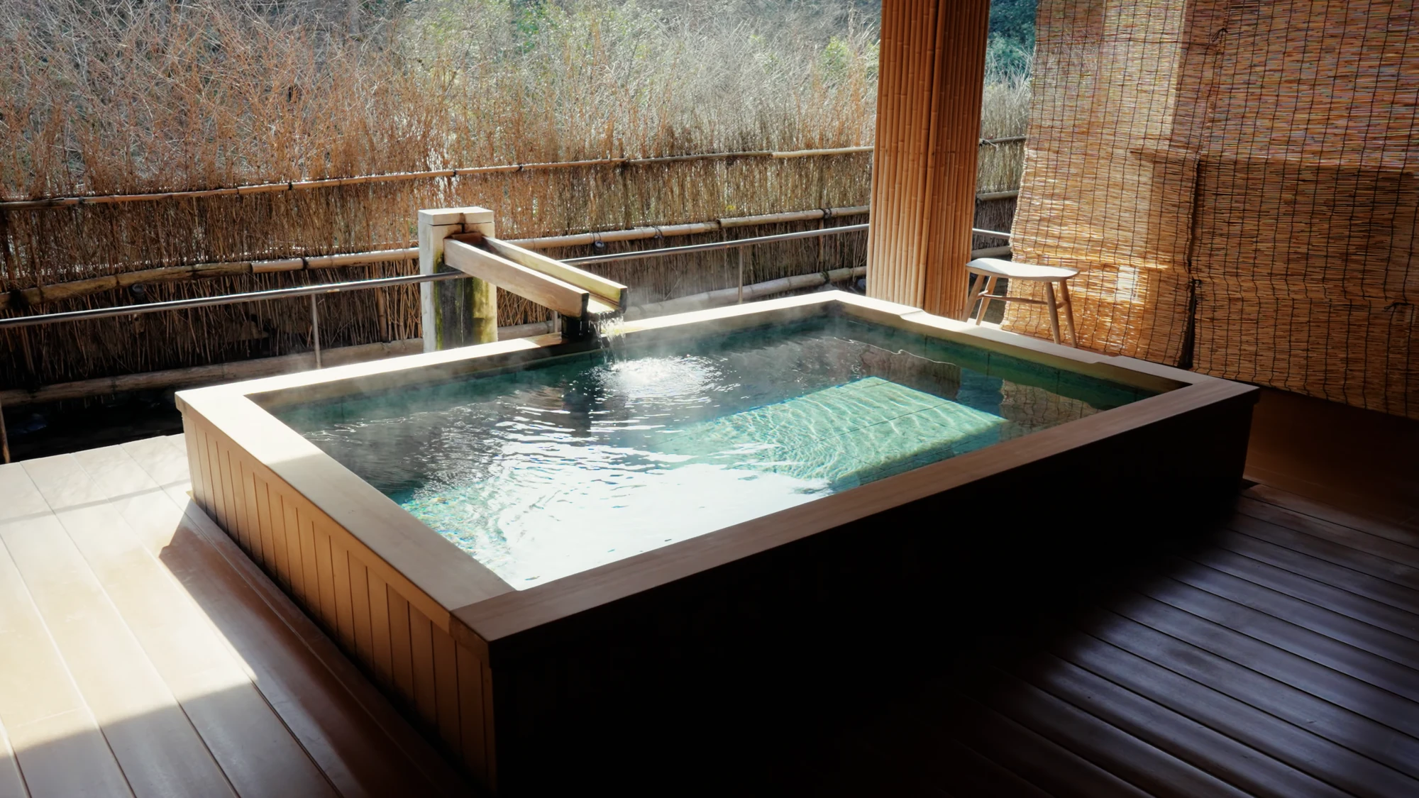 A small private hot spring bath screened by bamboo at a Kinosaki inn.