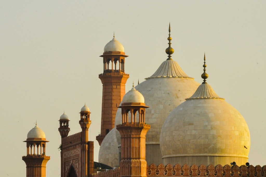 The majestic domes and minarets of the Badshahi Mosque in Lahore, Pakistan, stand tall against a clear sky, showcasing the grandeur of Mughal architecture and Islamic heritage.