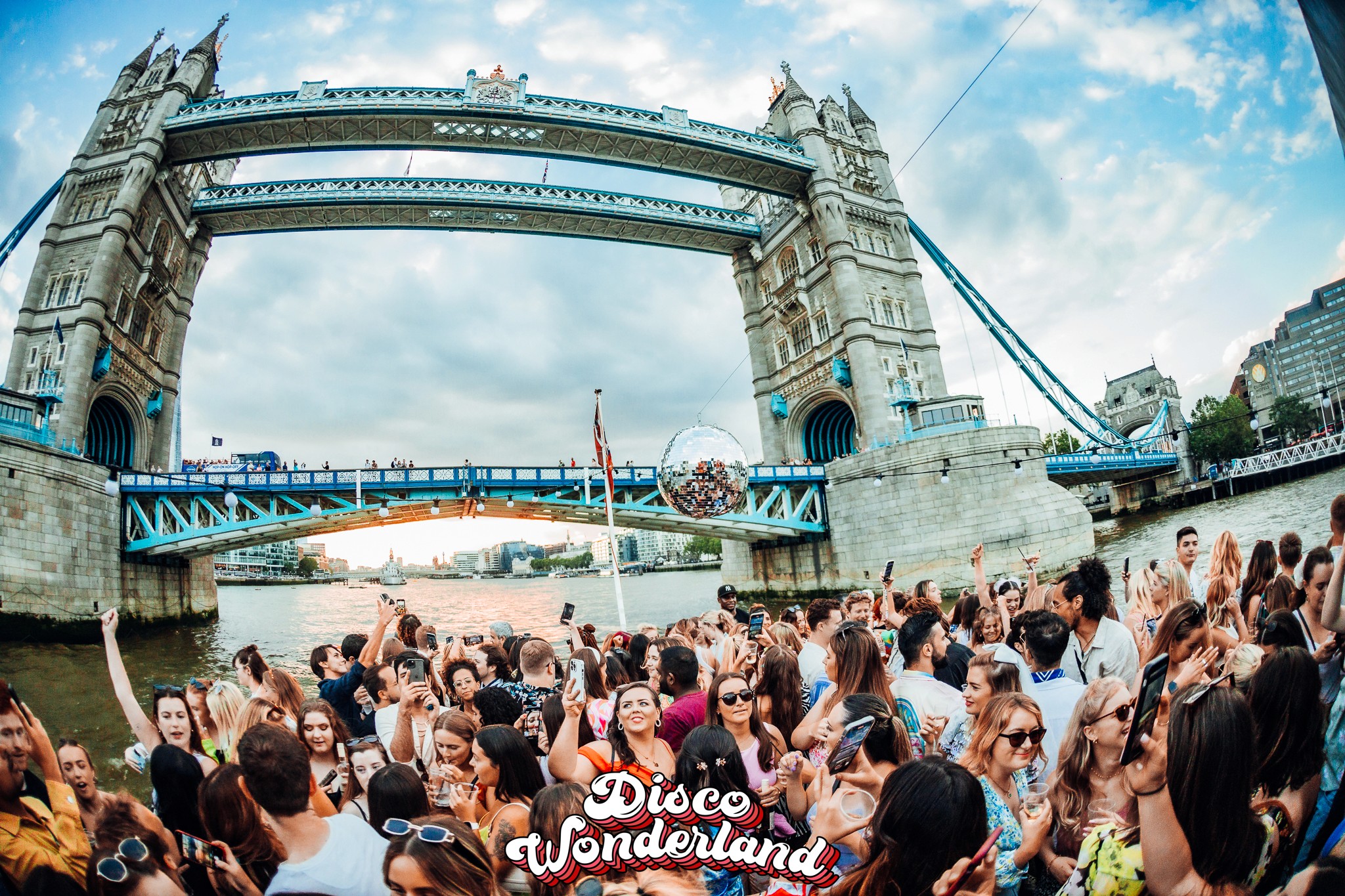 Guests in seventies-inspired outfits dancing under Tower Bridge at the Disco Wonderland ABBA party in London